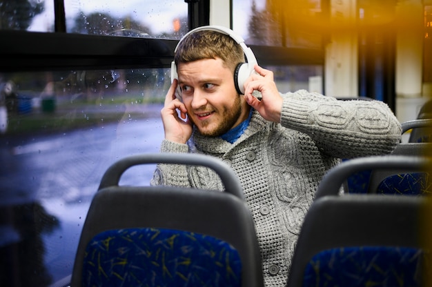 무료 사진 버스의 좌석에 헤드폰으로 젊은 남자