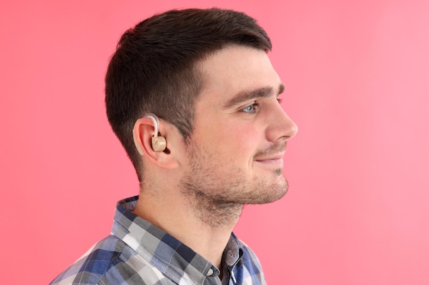 Young man with hearing aid on pink background Free Photo