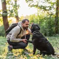 Foto gratuita giovane uomo con il suo cane nel parco