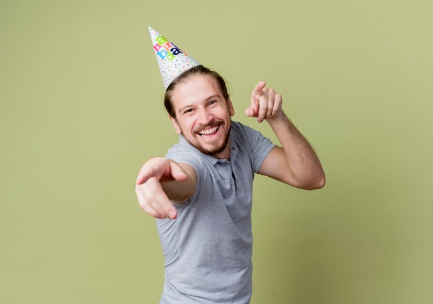 誕生日パーティーを祝うホリデーキャップを持つ若い男は、光に幸せで興奮しています