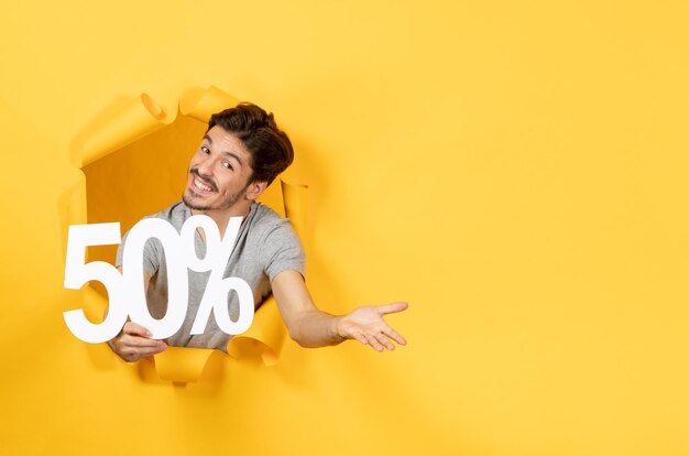 Young man with inscription sign on torn yellow background guy shopping sale