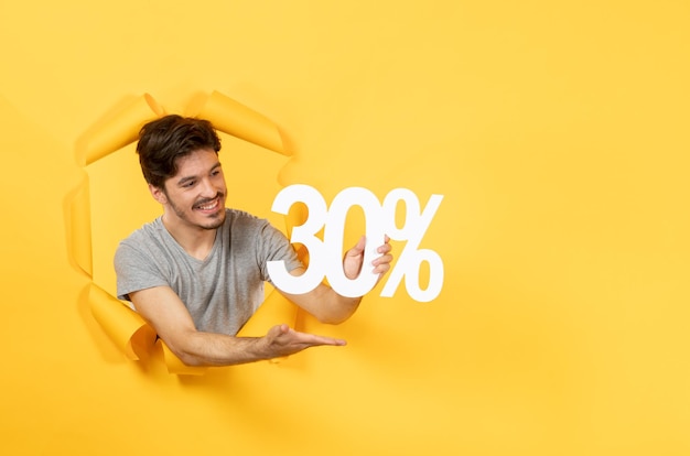 Young man with inscription sign on torn yellow background guy shopping