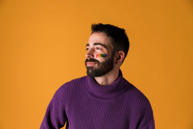 Young man with LGBT rainbow flag on face