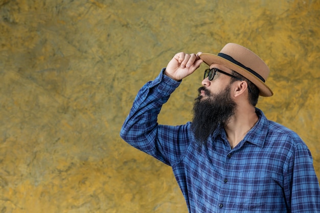 Young man with a long beard wearing a hat and glasses