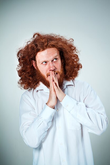 The young man with long red hair looking aside in thought