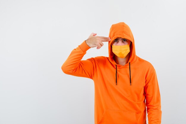 Young man with a mask holding a hand gun on white background