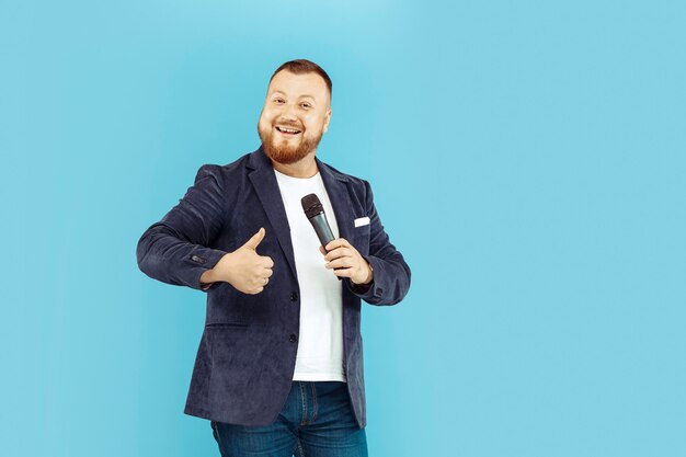 Young man with microphone on blue background, leading concept