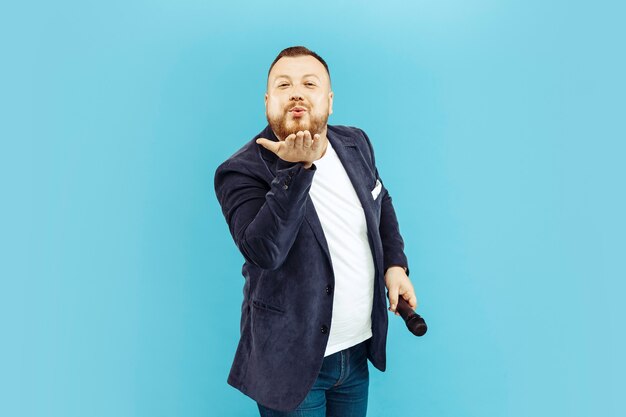 Young man with microphone on blue, leading concept