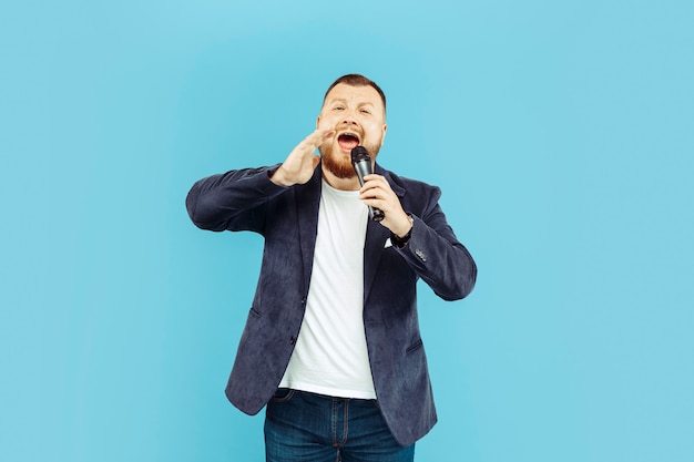 Young man with microphone on blue space, leading concept