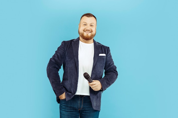 Free photo young man with microphone on blue space, leading concept