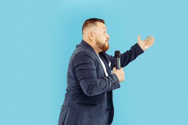 Young man with microphone on blue wall