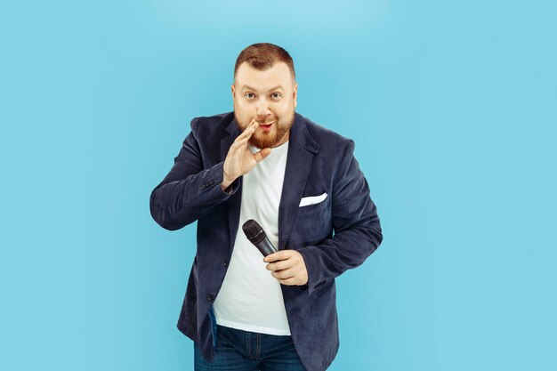 Young man with microphone on blue wall