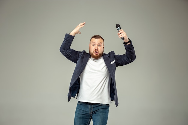 Young man with microphone on gray wall