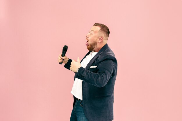 Молодой человек с микрофоном на розовом, ведущий с микрофоном