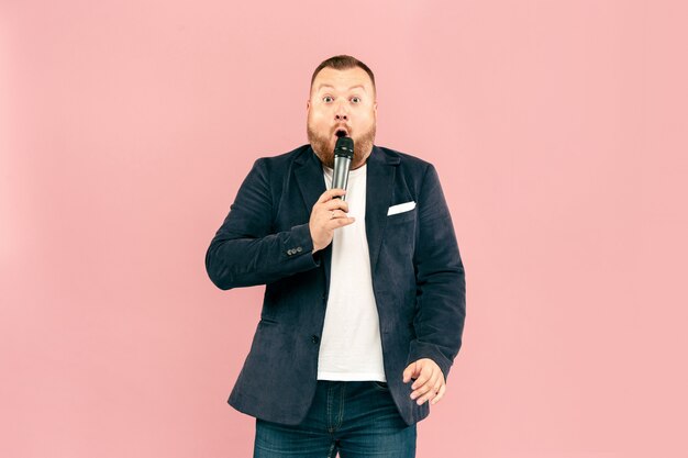 Young man with microphone on pink, leading with microphone