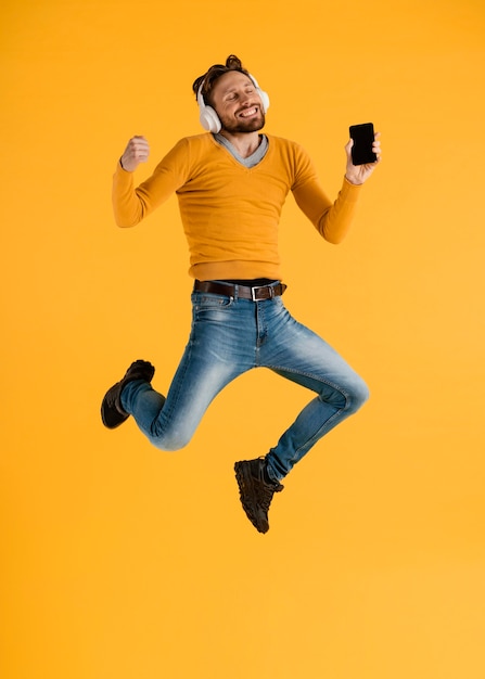 Young man with mobile and headphones jumping