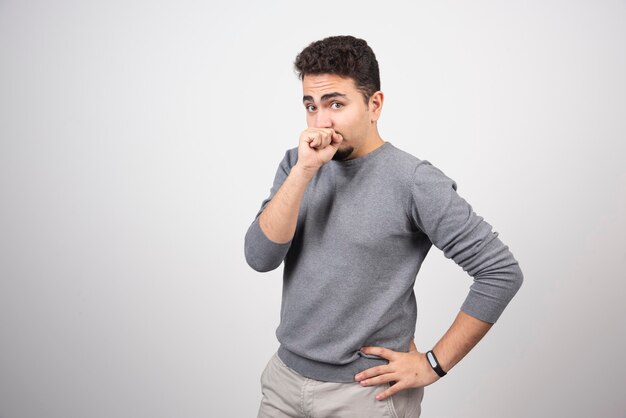 Young man with mustache putting fist to mouth.