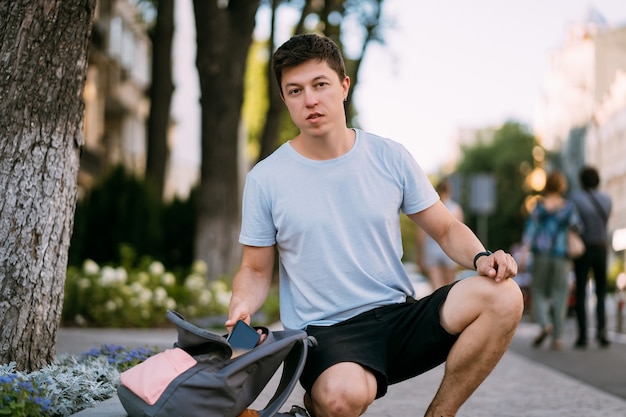 Young man with open backpack on the street. Portrait of a young man