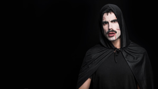 Young man with pale face and scars posing in Halloween costume