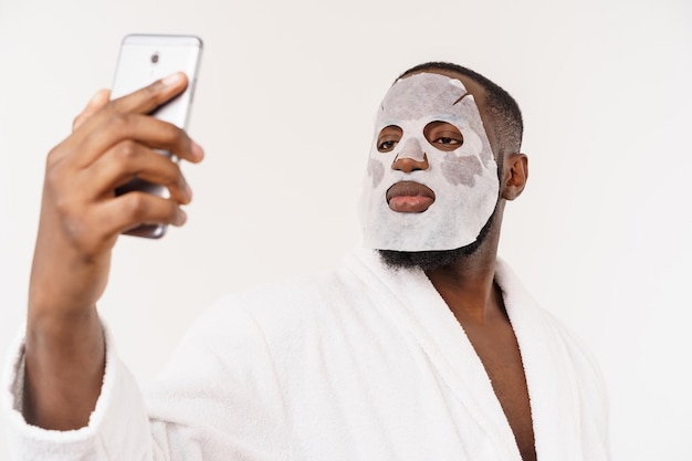 A young man with paper mask on face looking shocked with an open mouth isolated on a white background