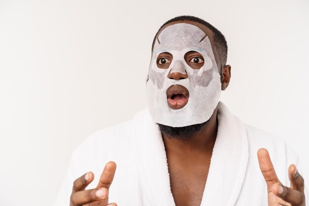 A young man with paper mask on face looking shocked with an open mouth isolated on a white background