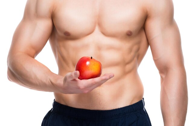 Young man with perfect body holding red apple in his hand 