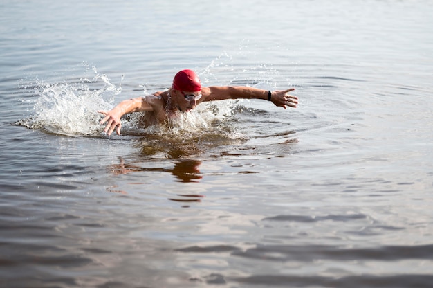 Young man with red cap swimming in lake