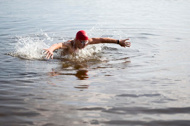湖で泳いでいる赤い帽子の若い男