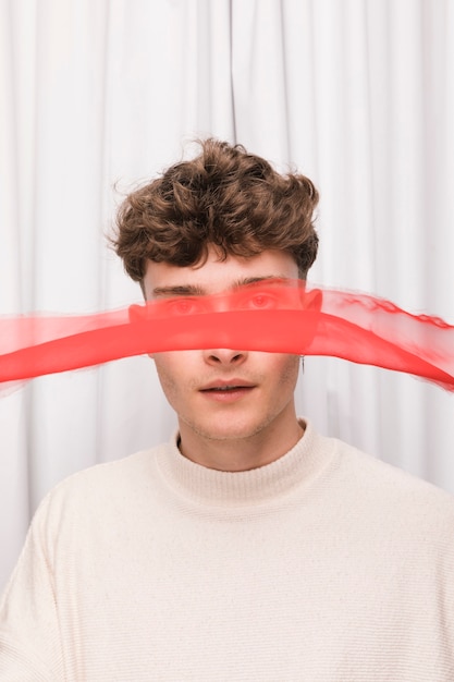 Free photo young man with red ribbon in front of face