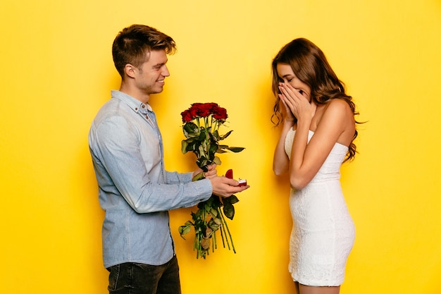 Young man with ring in box making proposal of marriage to his beautiful girlfriend