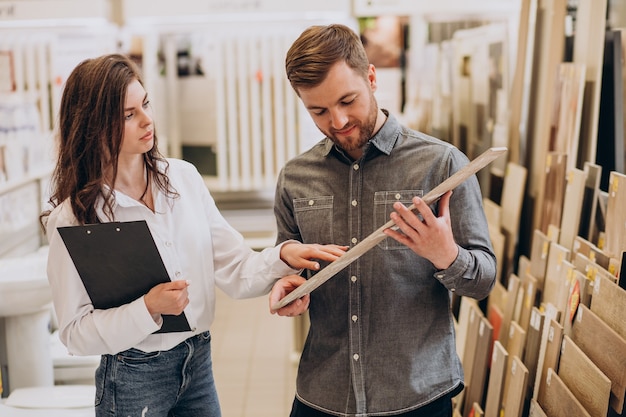 Young man with sales woman choosing tiles at building market