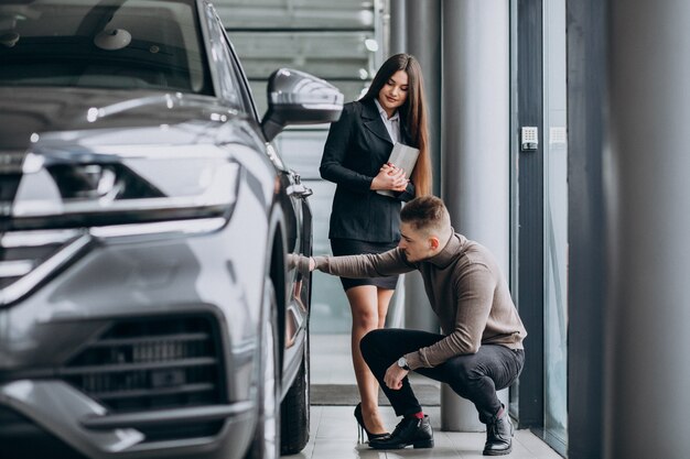 Young man with saleswoman at a car showroom