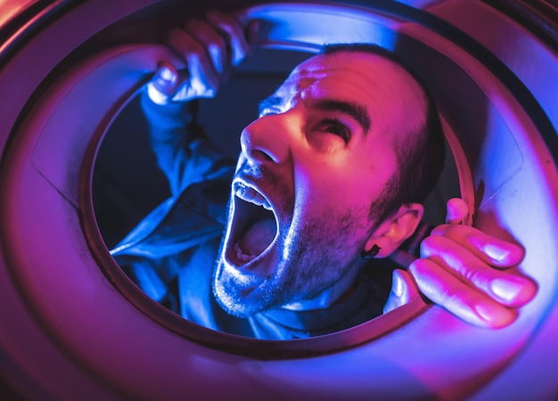 Young man with a scared face looking into the washing machine