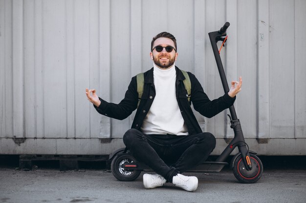 Young man with scooter, sitting on the ground