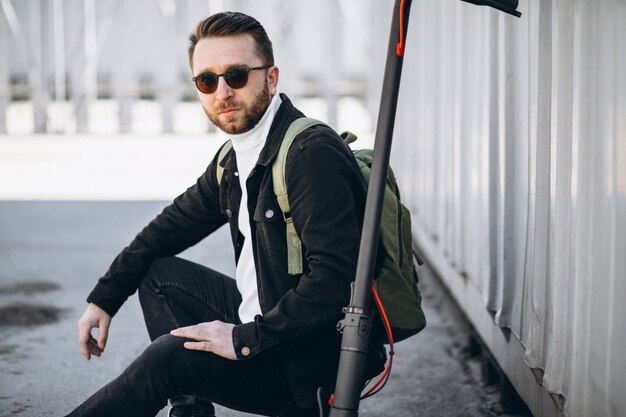 Young man with scooter, sitting on the ground