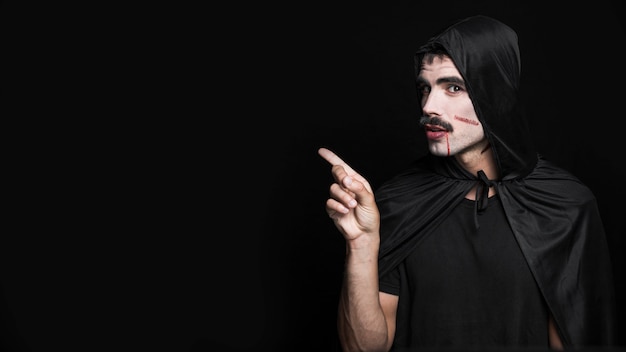 Young man with scratches painted on pale face posing in Halloween costume