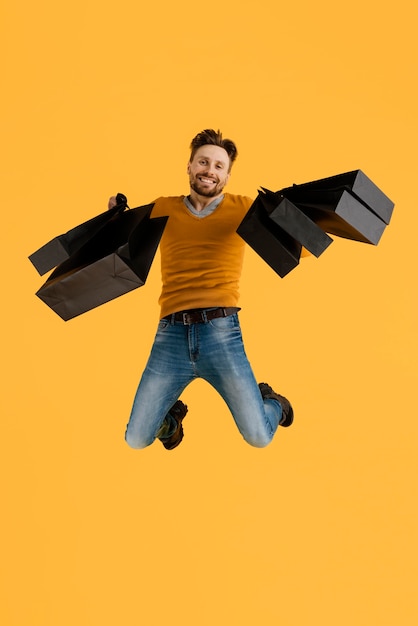 Young man with shopping bags jumping