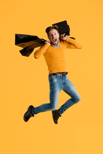 Free photo young man with shopping bags jumping