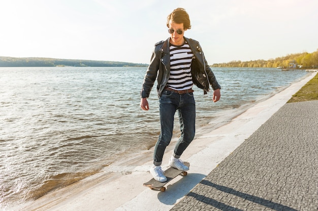 Free photo young man with a skateboard near the sea