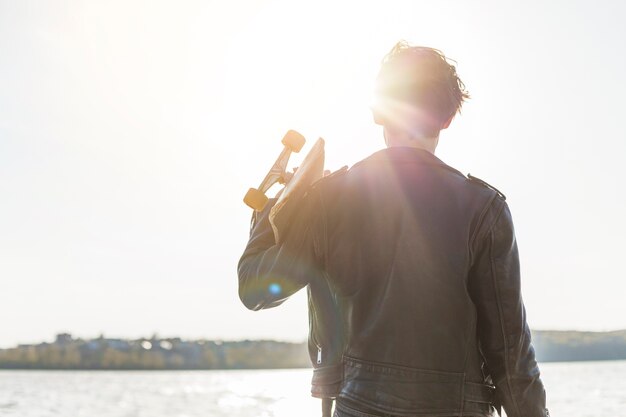 海のそばのスケートボードを持つ若い男