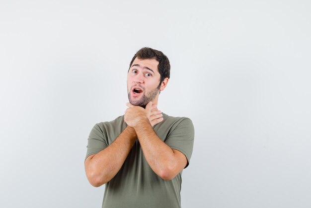 Young man with strangling hands on his neck on white background