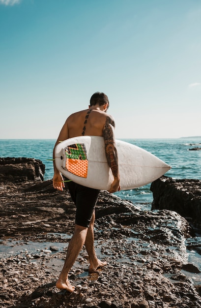 Foto gratuita giovane con tavola da surf andando ad acqua