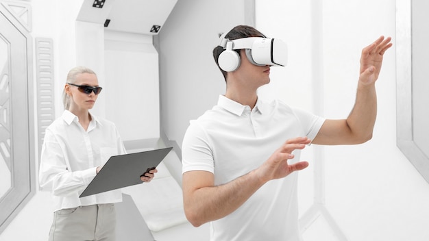 Young man with virtual reality simulator and woman testing