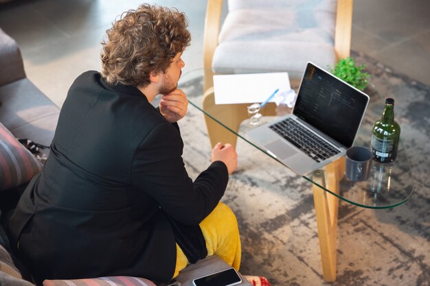 Young man without pants but in jacket working on a computer, laptop.