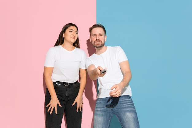 Young man, woman in casual on pink, blue bicolored background.