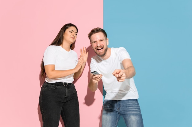 Young man, woman in casual on pink, blue bicolored background.