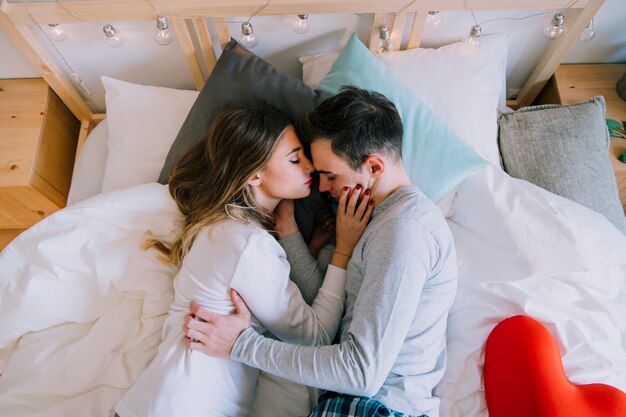 Young man and woman cuddling in bed