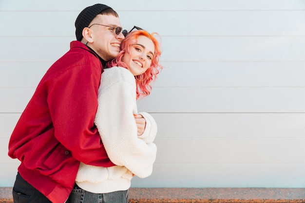 Free photo young man and woman embracing and laughing on street