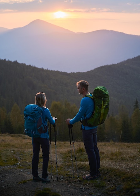 Young man and woman hiking in mountains during sunrise