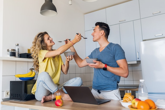 若い男性と女性の朝のキッチンで健康的な楽しい朝食を持っていることの愛